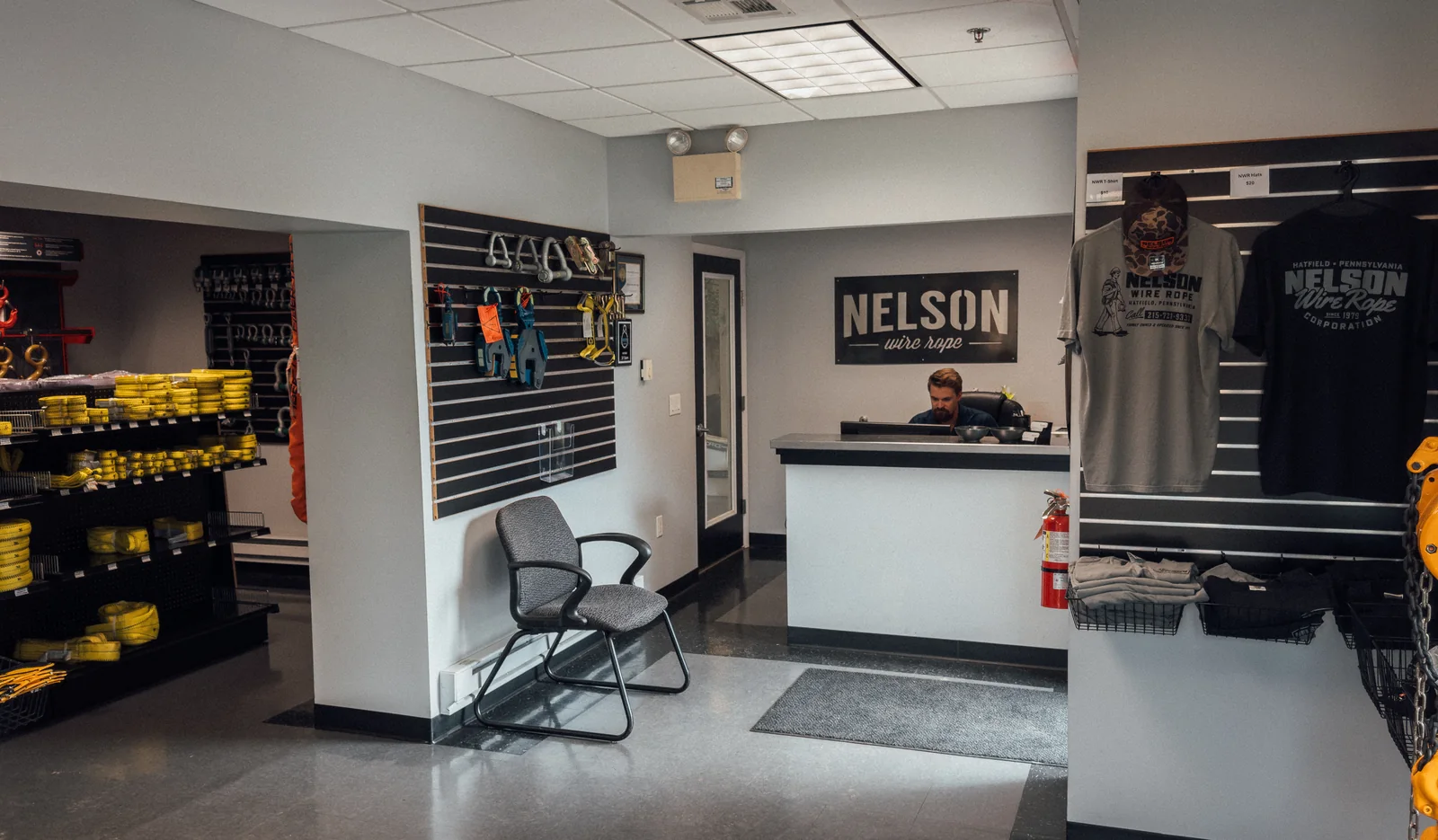 The front of the Nelson Wire Rope showroom: the service counter under the Nelson sign, web slings racked on the left and clamps and hardware on the display wall