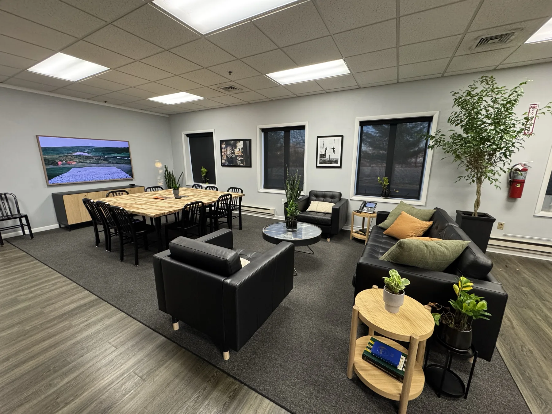 The customer lounge and meeting room at Nelson Wire Rope: a long butcher-block table with seating for a dozen, leather couches and armchairs, and plants along the windows